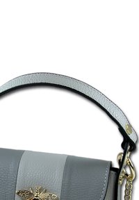 Gray leather handbag with a smooth texture, featuring a gold moth accent and a light gray handle with a textured finish.