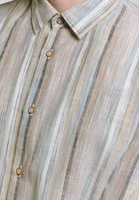 Overhemd met knoopsluiting van lichte stof heeft verticale strepen in beige, lichtblauw en grijs. Opvallende details zijn de kraag en de knoopsluitingen.