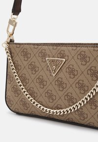 Sac à épaule marron à motifs avec une bandoulière en chaîne dorée et un logo Guess triangulaire. Matériau durable et design structuré.