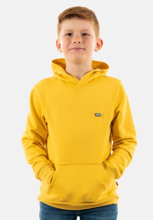 Sudadera amarilla con bolsillo canguro, puños y dobladillo acanalados. Presenta un pequeño logo de la marca en el pecho. Fabricada con un tejido suave y grueso.