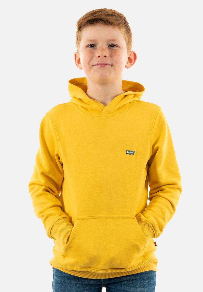 Sudadera amarilla con bolsillo canguro, puños y dobladillo acanalados. Presenta un pequeño logo de la marca en el pecho. Fabricada con un tejido suave y grueso.