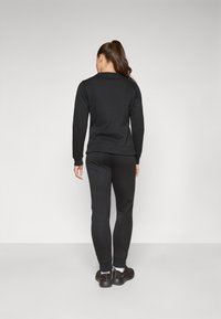 Svart hverdags hettegenser og matchende joggebukser, med et enkelt design og myk tekstur, sett bakfra. Ingen synlige logoer eller mønstre.
