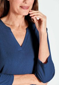 Navyblaues V-Ausschnitt-Oberteil aus weichem Stoff, mit einem lockeren Schnitt und Dreiviertelärmeln mit einer leichtenöffnung am Abschluss.