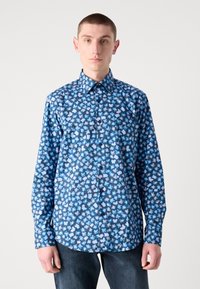 Chemise à manches longues à boutons de couleur bleu avec un motif floral en bleu clair et blanc. Tissu lisse, col, et boutons noirs. Coupe régulière.