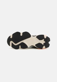 Black rubber athletic shoe sole with textured surface, featuring a white midsole and a small orange accent on the heel.