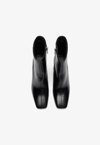 Black leather ankle boots with a smooth texture, pointed toe, and side zippers, featuring a sleek, minimalist design.