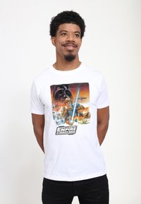 Wit katoenen T-shirt met een kleurrijke grafische print van "The Empire Strikes Back" met personages, een lichtzwaard en ruimte-elementen.