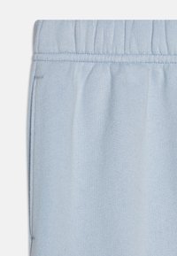 Lyseblå joggebukser med elastisk midje, myk tekstur og flatlock sømdetalj langs siden for en ren finish.