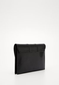 Pochette noire texturée avec une finition brillante, de forme rectangulaire, rabat repliable, et coutures discrètes sur le devant.