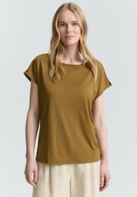 T-shirt a maniche corte, verde oliva, con scollo rotondo e vestibilità rilassata, realizzata in tessuto morbido e liscio.
