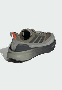 Ultraboost running shoe with a gray and black color scheme, textured mesh upper, thick cushioned sole, and red accent on the heel.