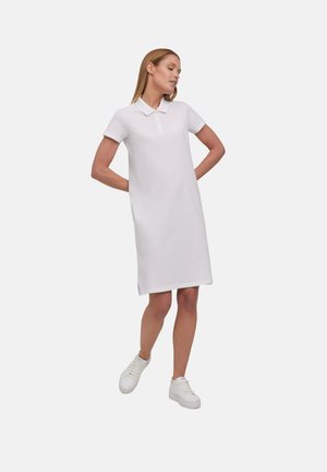 Witte polo jurk met korte mouwen, kraag en een drie-knopen sluiting. Regular-fit ontwerp met zijsplitten aan de zoom. G gedragen met witte sneakers.