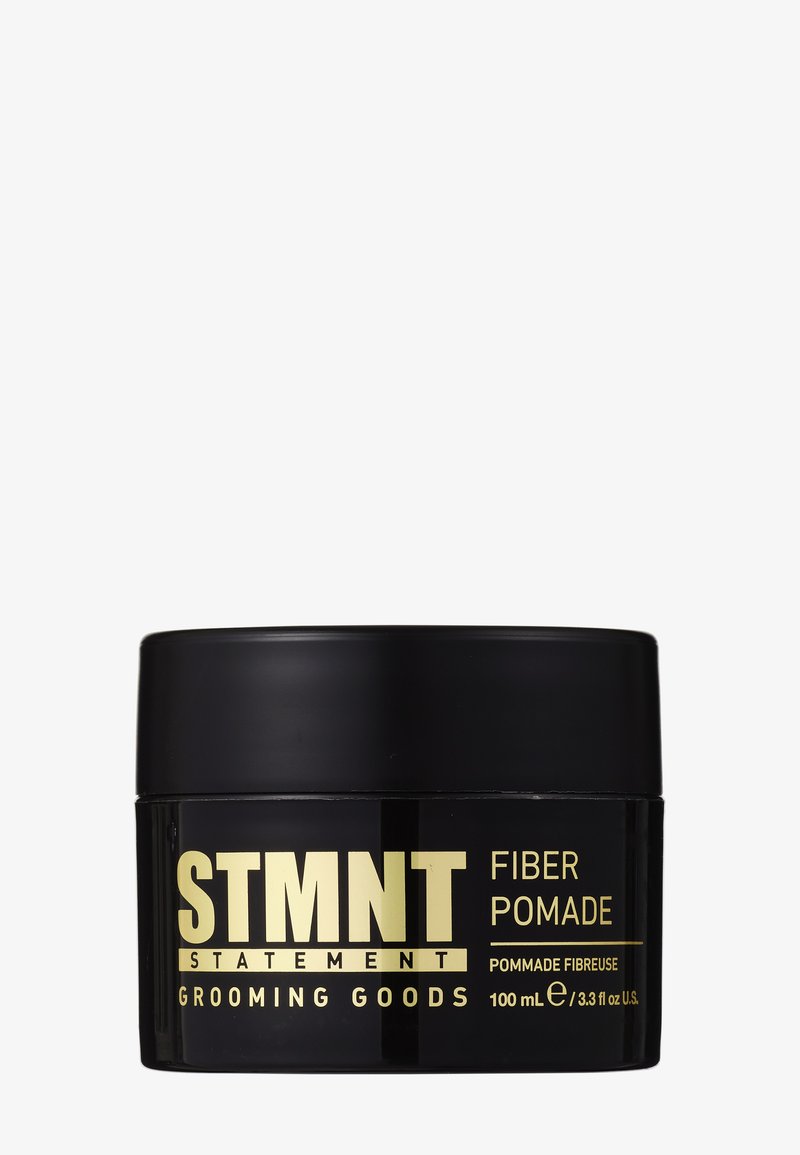 Zwarte STMNT fiber pomade container met gouden tekst, gelabeld als verzorgingsproducten, 100 ml (3,3 fl oz) inhoud, op witte achtergrond.