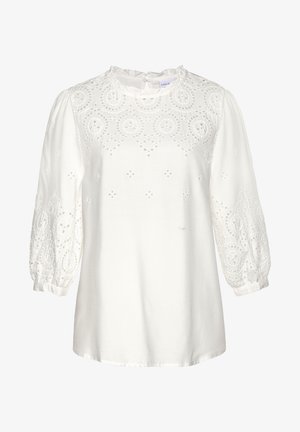 Valkoinen paita, jossa on teksturoitu, brodeerattu kuvio, joka sisältää pyöreitä muotoja, puffihelmihihat ja pieni napin suljenta takana.