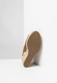 Sandale à talon compensé en suede marron avec un talon en jute tressé, affichant des détails de logo sur la semelle extérieure et une semelle intérieure lisse et texturée. Taille 37.