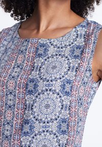 Robe sans manches présentant des motifs floraux bleu et blanc complexes avec des accents rouges et des designs géométriques. Tissu lisse avec un col rond.