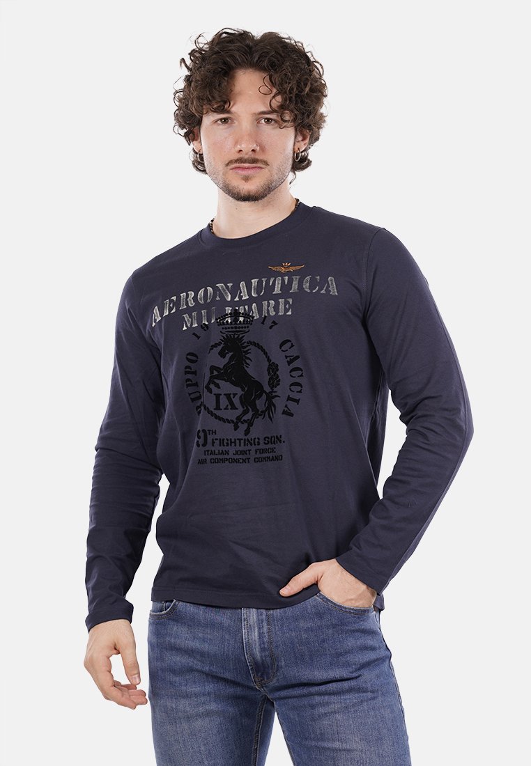 T-shirt a maniche lunghe blu navy con scollo a girocollo, caratterizzato da una stampa grafica che include un cavallo e un testo. Abbinato a jeans blu.