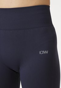 Marine kompresjonsleggings med ribbet midjebånd. Har en liten sølvfarget logo på nederste side. Glatt tekstur med en tettsittende design.