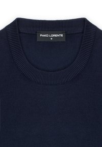 Granatowy sweter z okrągłym dekoltem, ribbowanym dołem i mankietami. Materiał wydaje się gładki, posiada metkę z napisem "PAKO LORENTE" i rozmiarem M.