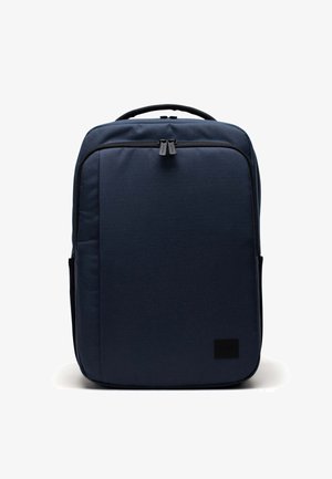 Marineblauwe rugzak van duurzaam stof, met een rechthoekige vorm, twee ritstrekkers en een zwart logo-label aan de voorkant.