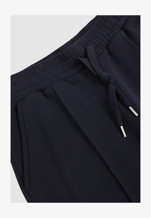 I pantaloni giapponesi blu navy presentano una vita elastica con cordino, tasche laterali e una texture liscia e morbida. Aghetti color argento sul cordino.