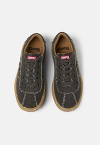 Sneakers in tela grigia scura con suole in gomma marrone, caratterizzate da cuciture testurizzate e occhielli neri. Logo rosso sulla linguetta e sulla soletta.