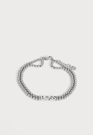 Bracelet perlé à double rang en argent avec les lettres "BOSS" au centre et une fermeture à mousqueton sur un fond uni.