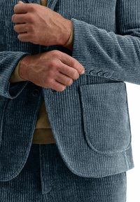 Grijze corduroy blazer met verticale strepen, voorzien van een pocket, knoopsluiting en een zachte textuur. Draag het over een bruine trui.
