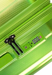 Grüner Hartschalenkoffer mit strukturiertem Finish, doppelten Reißverschlüssen, Kombinationsschloss und farblich abgestimmten Akzenten in verschiedenen Grüntönen.