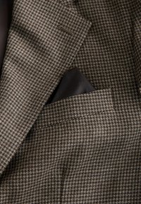 Brown houndstooth pattern blazer with a textured fabric. Includes a pocket square tucked into the breast pocket. Inner lining visible.