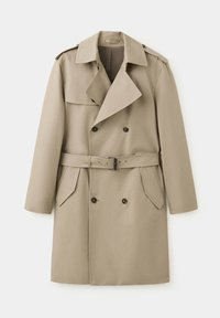 Trench-coat beige à double boutonnage avec large col, ceinture à la taille, épaulettes et deux poches avant à rabat.