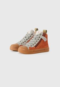 Høye sneakers i oransje og grå. Har en overdel i semsket skinn, gummisåle og glidelåsdetaljer. Designet med grå snørebånd og en trekk-flap.
