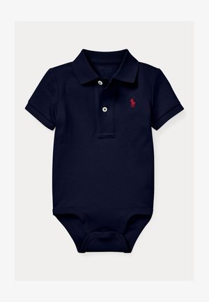 Salopetă polo de culoare bleumarin, fabricată din bumbac, cu un logo brodat roșu, trei butoane albe și închidere prin botoane la baza. Mâneci scurte.
