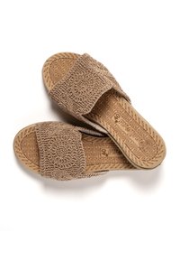 Sandalias tipo slip-on beige con correas de tela texturizada que presentan patrones intrincados y una suela de goma con diseño.