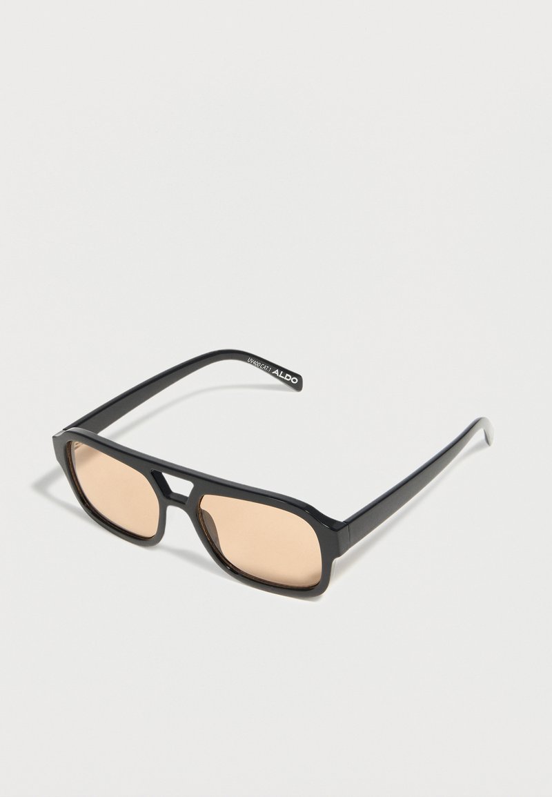 Lunettes de soleil rectangulaires noires avec des verres fins teintés beige et un pont en forme de trou de serrure, marquées ALDO sur la branche.