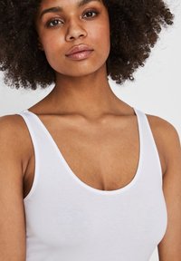 Débardeur blanc à encolure dégagée, fabriqué en tissu lisse et léger, avec des bretelles fines et une silhouette ajustée.