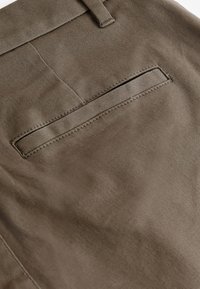Brown fabric trousers with a smooth texture, featuring a back pocket with a clean, stitched accent and a subtle sheen.