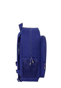 Niebieski plecak z dwiema komorami zapinanymi na zamek, siatkową kieszenią boczną i wyściełanymi ramiączkami, pokazany z boku na białym tle.