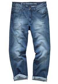 Jeans de mezclilla azul oscuro con un lavado desgastado, diseño de cinco bolsillos, dobladillos enrollados y una cinturilla etiquetada como "Solo para hombres de verdad".