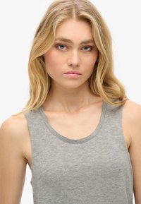 Szary, bezrękawnik z miękkiego, teksturowanego materiału. Okrągły dekolt, luźny krój oraz subtelne logo na wysokości klatki piersiowej.