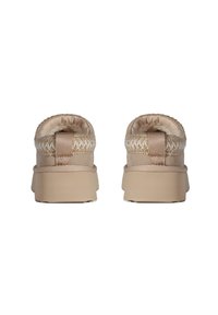 Beige instap schoenen met een textuur bovenkant, gevlochten accenten en een gevoerde kraag. Dikke, platte zool voor ondersteuning en comfort.