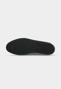 Semelle de chaussure en caoutchouc noir avec des motifs de bande de roulement texturés et le nom de la marque "GEOX" embossé près du centre.