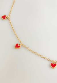 Zlatý náramek s řetízkem, který obsahuje čtyři červené srdíčkové přívěsky, z nichž každý má lesklou emailovou povrchovou úpravu a hladký, zaoblený tvar.