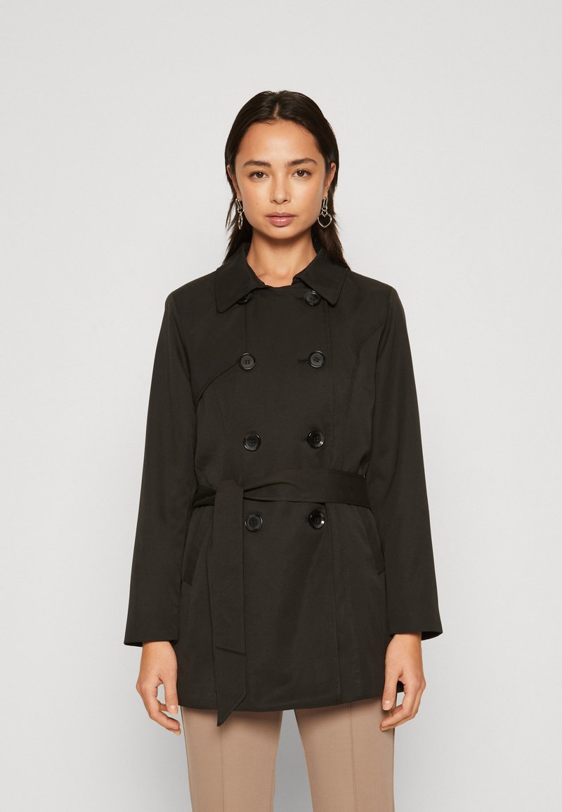 Trench coat nero doppiopetto con vita cintrata, grandi bottoni e colletto classico. Realizzato in tessuto liscio e leggero.