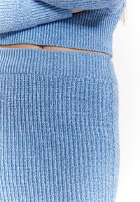 Blauw gebreid twee-delig set met een geribbelde structuur, een cropped top en een hooggewaisted onderstuk. Subtiele lichtblauwe en donkerblauwe patronen.
