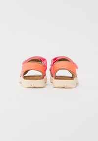 Bakifrån vy av sandaler med rosa och orange remmar, texturerat tyg och en ljusfärgad dämpad sula med greppmönster.