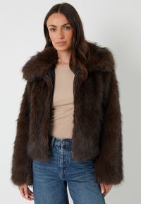 Brauner Kunstfelljacke mit breitem Kragen, Reißverschluss vorne und cropped Design. Glatte Lederakzente und lange Ärmel. Strukturierte Oberfläche.