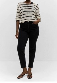 Černé vysoké džíny spárované s krémovým a černým pruhovaným pleteným svetr. Svetr má volný střih a široký výstřih.