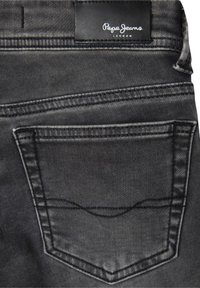 Crne traperice od denima s stražnjim džepom ukrašenim zakrivljenim šavom, kožnom etiketom s utisnutim natpisom "Pepe Jeans" i elegantnim završetkom.