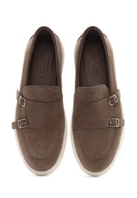 Brown suede slip-on shoes with dual metal buckle accents, white rubber soles, and stitched detailing on the vamp and sides.